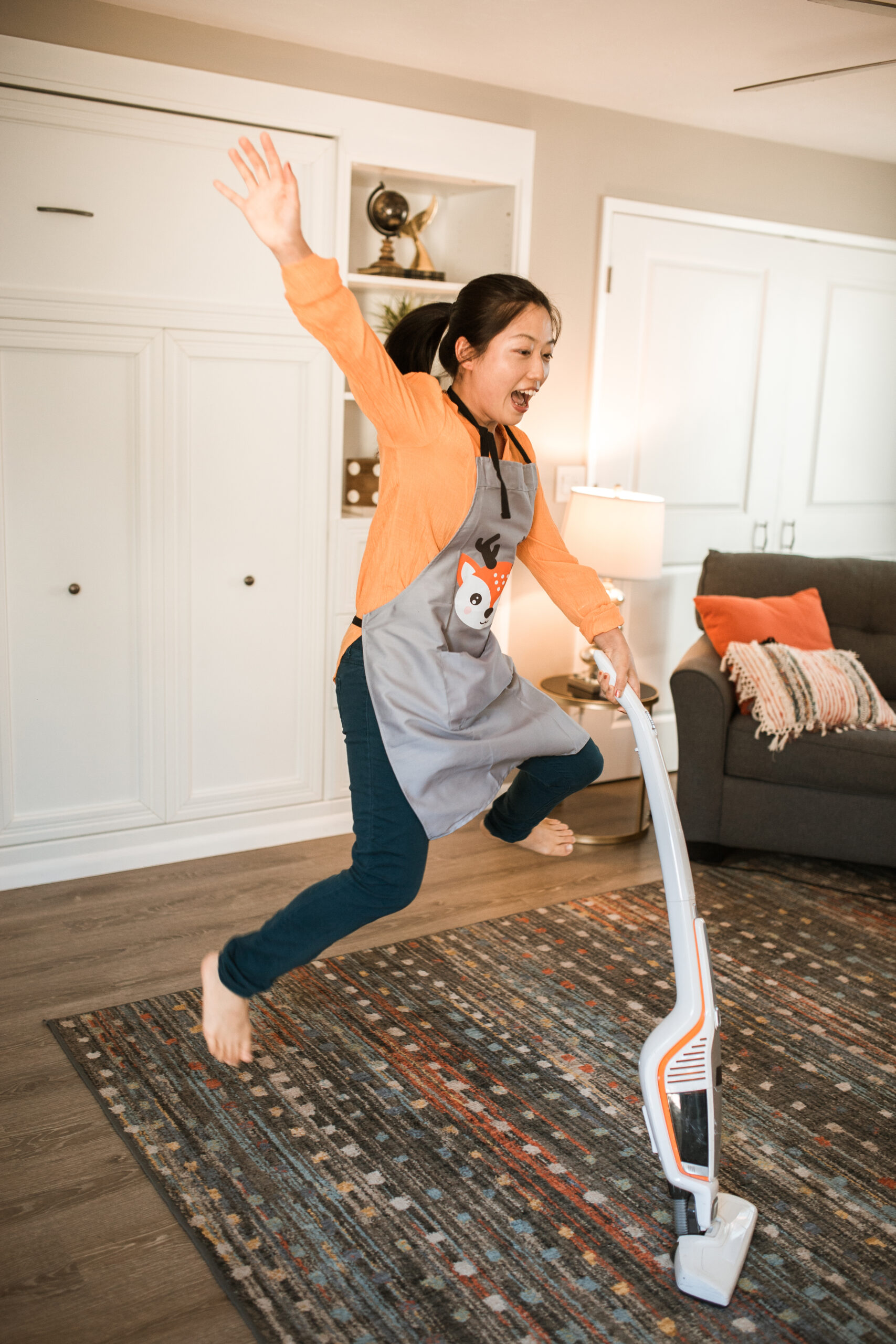 A woman jumping while using a vacuum cleaner