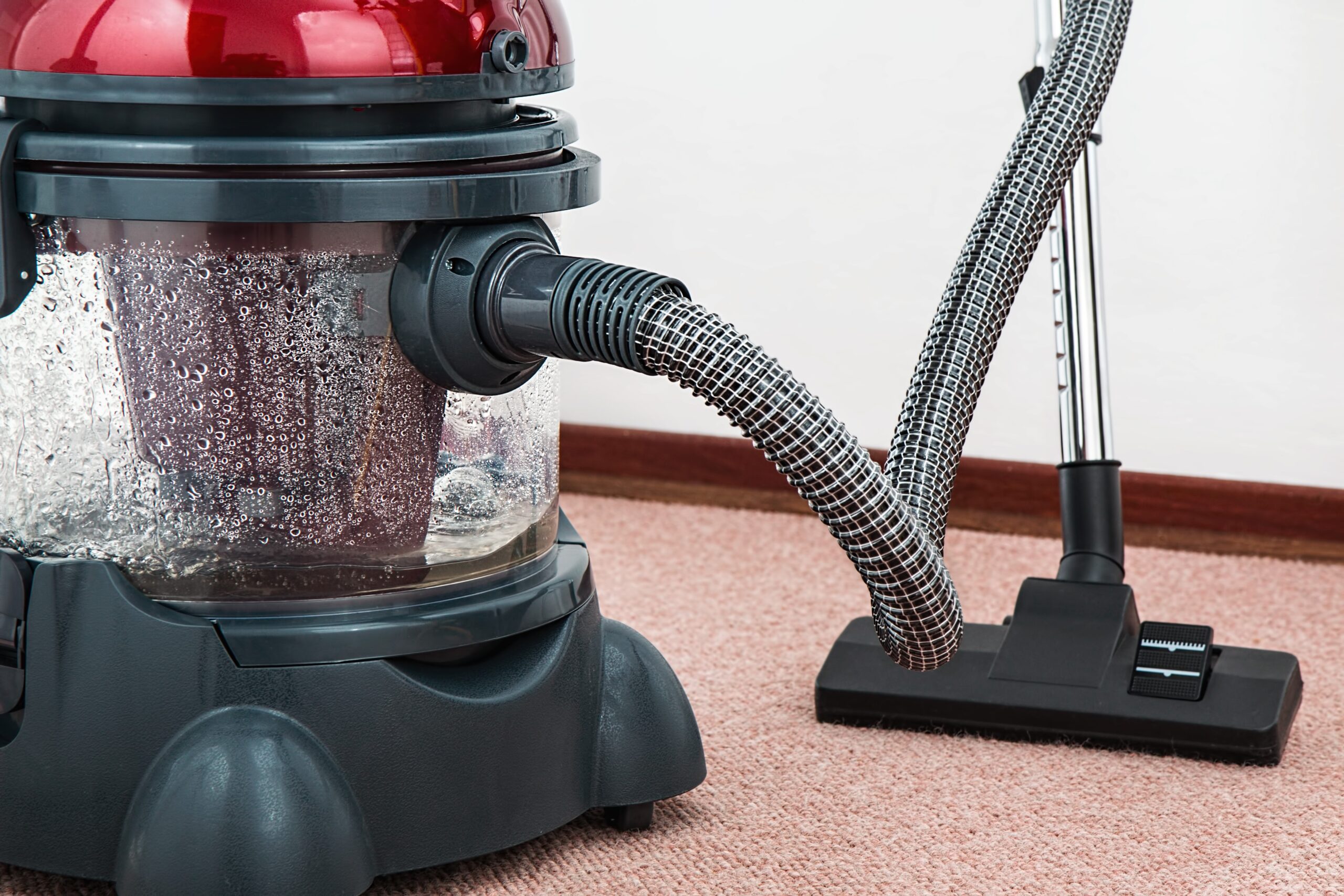 Black and red canister vacuum cleaner on floor