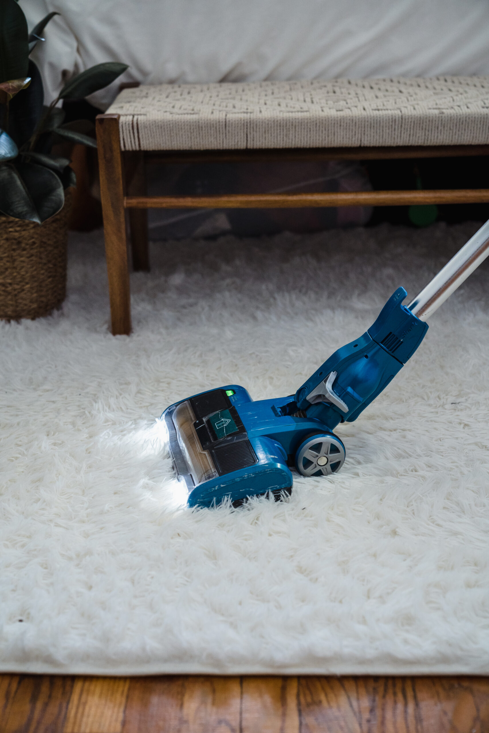 Blue vacuum cleaner on white fur carpet
